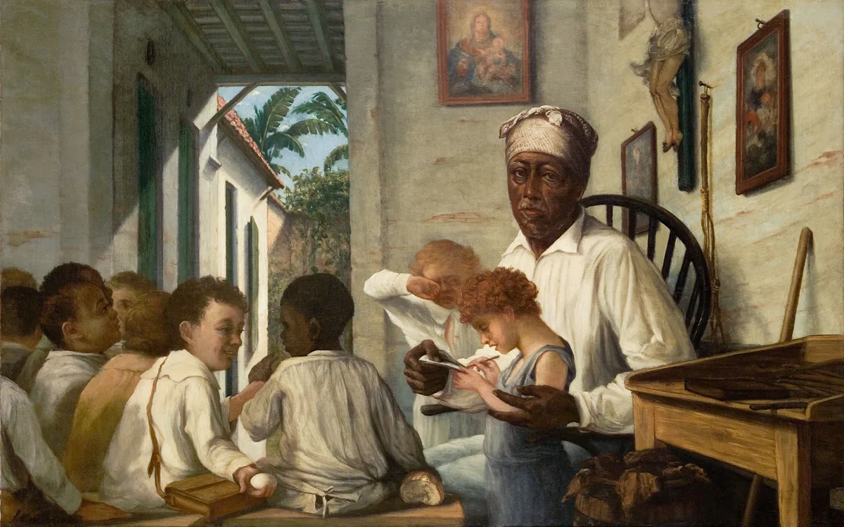 A Black schoolteacher helps a child with a lesson while other children study around him.